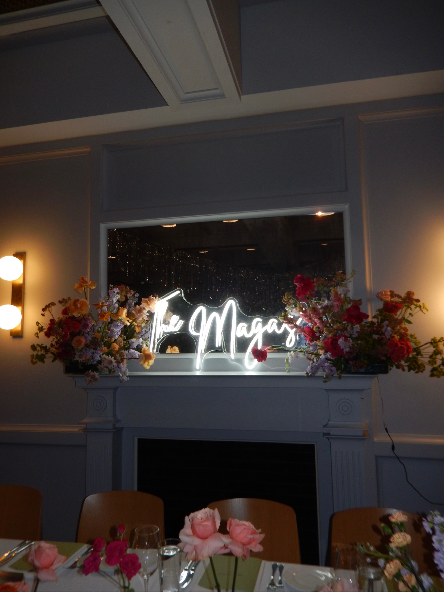 Neon sign saying "The Magas" with floral arrangements on either end, in reception space at The Line hotel in Washington DC