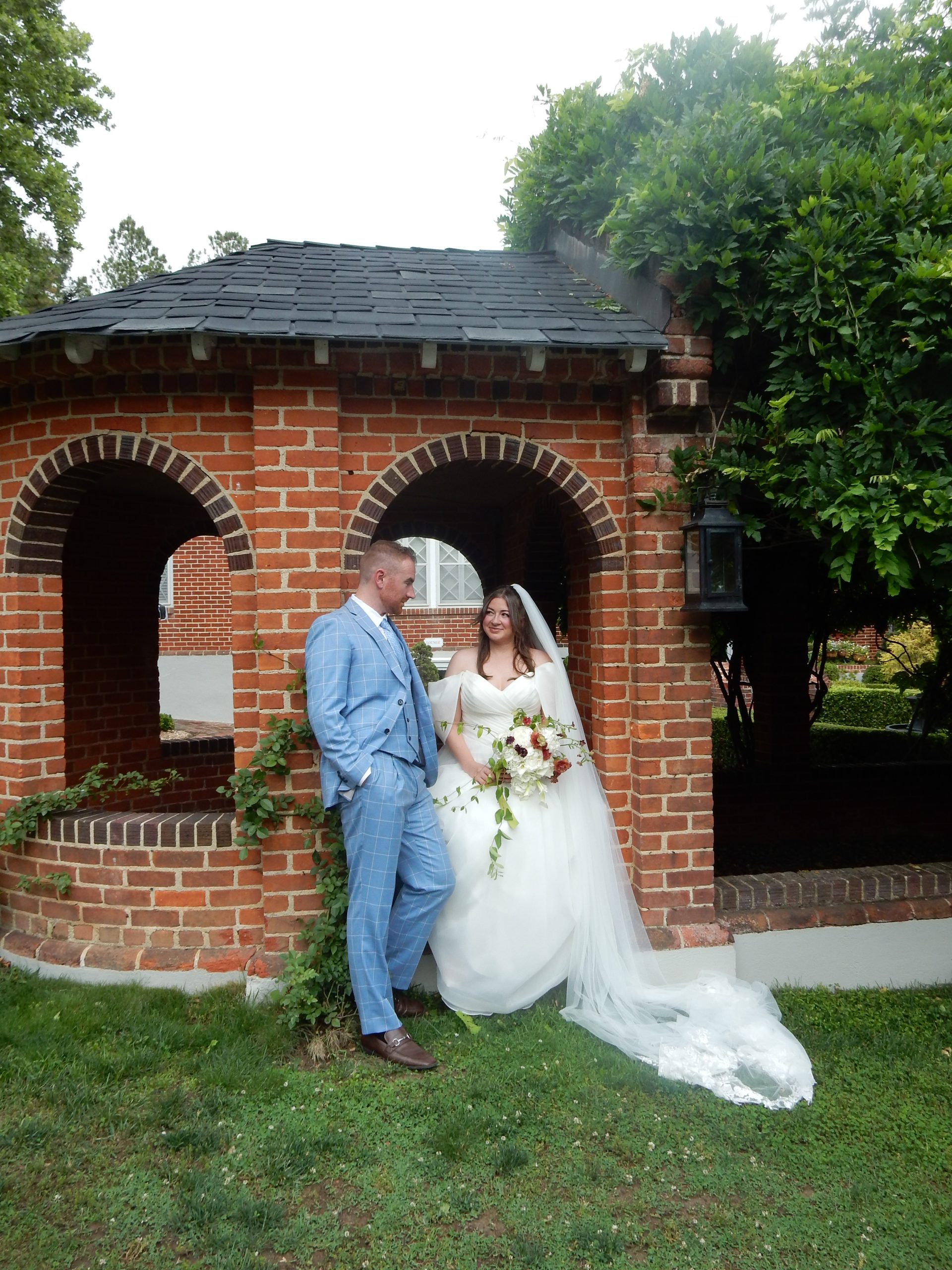 bride and groom sitting under a brick arch in the garden at mankin mansion
