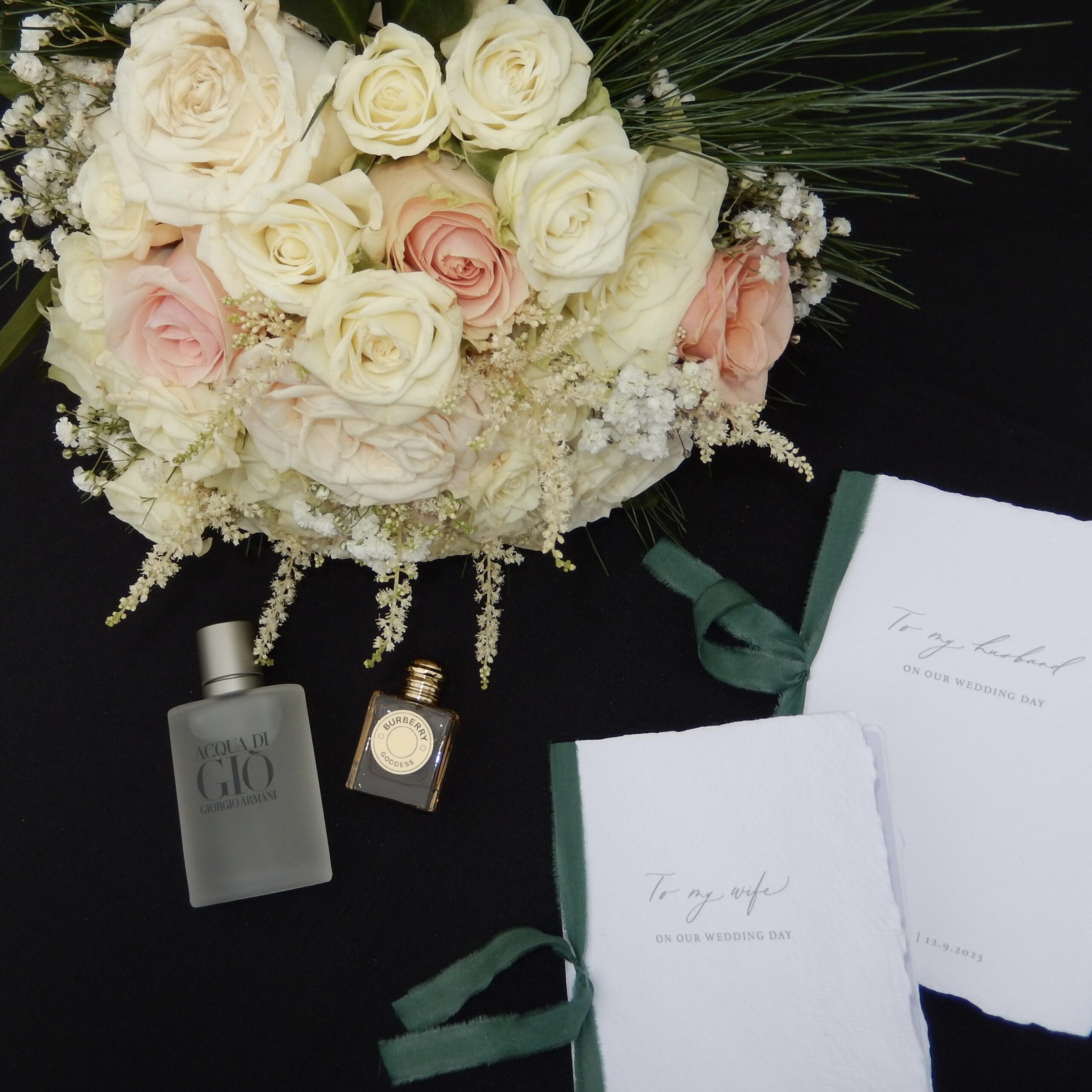 wedding details including vow books, bridal bouquet, perfume and cologne