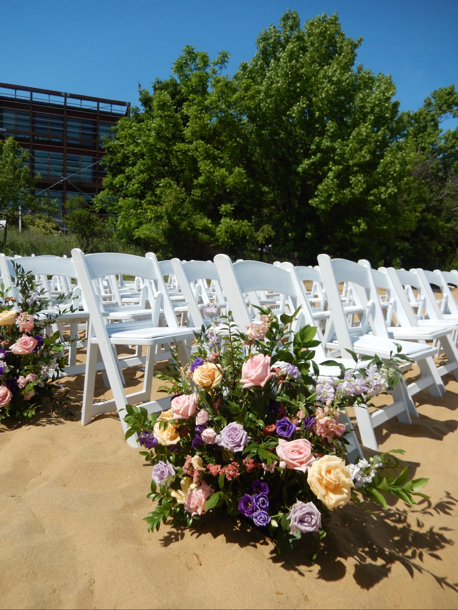 beach wedding ceremony setup with colorful yellow, pink, and purple flowers