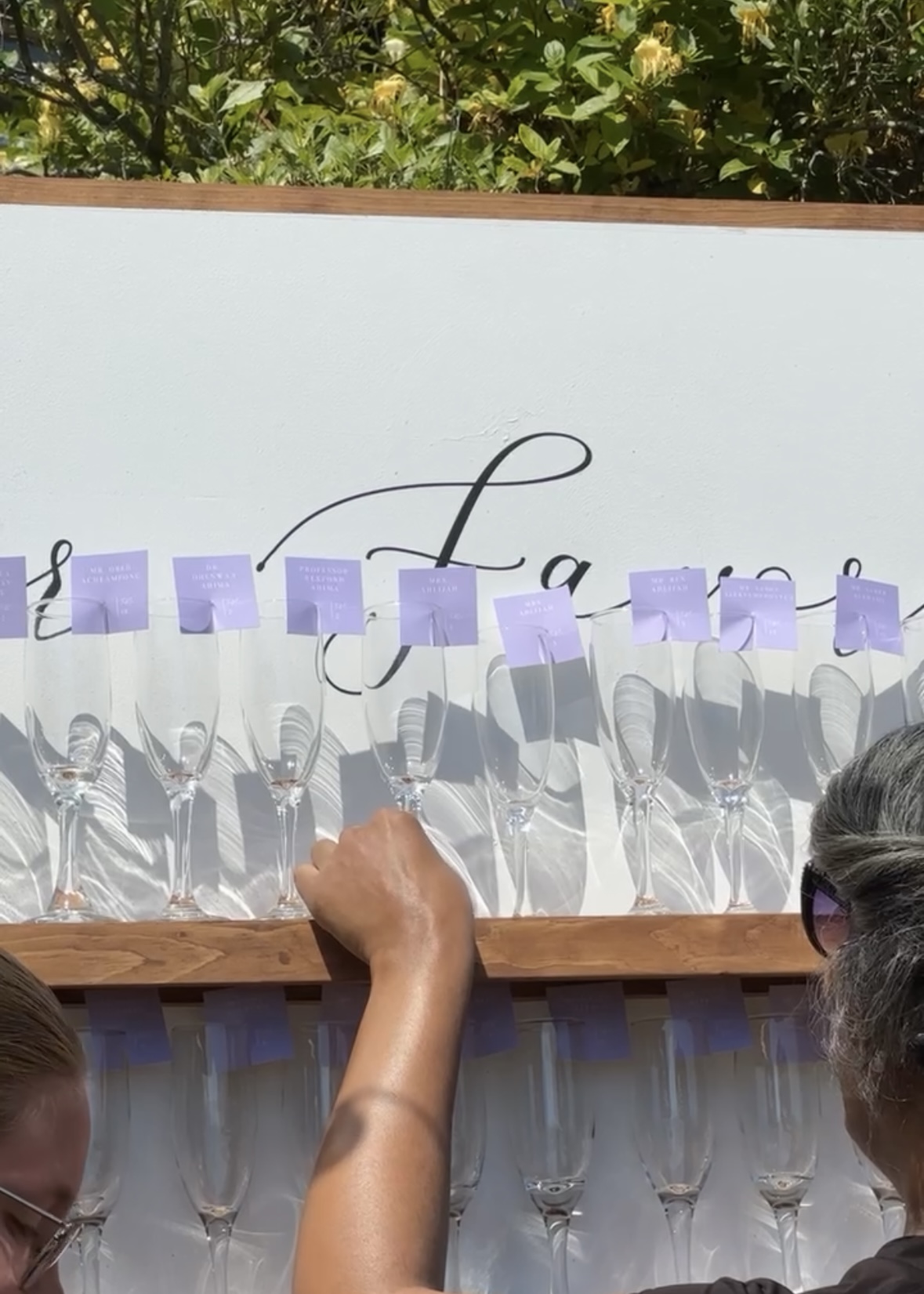 wedding planner placing champagne flutes with purple name tags on a shelf 